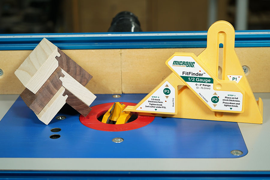Router table with yellow gauge, joinery wood samples, and router bit for precision woodworking.