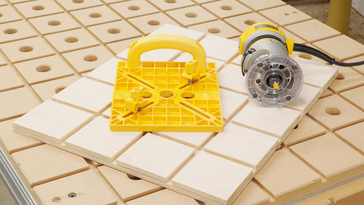 Woodworking router tool and yellow push block on CNC work table with MDF grid and holes