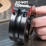 Hand holding a woodworking shaper cutter with screws labeled 'DO NOT LOOSEN' for safety
