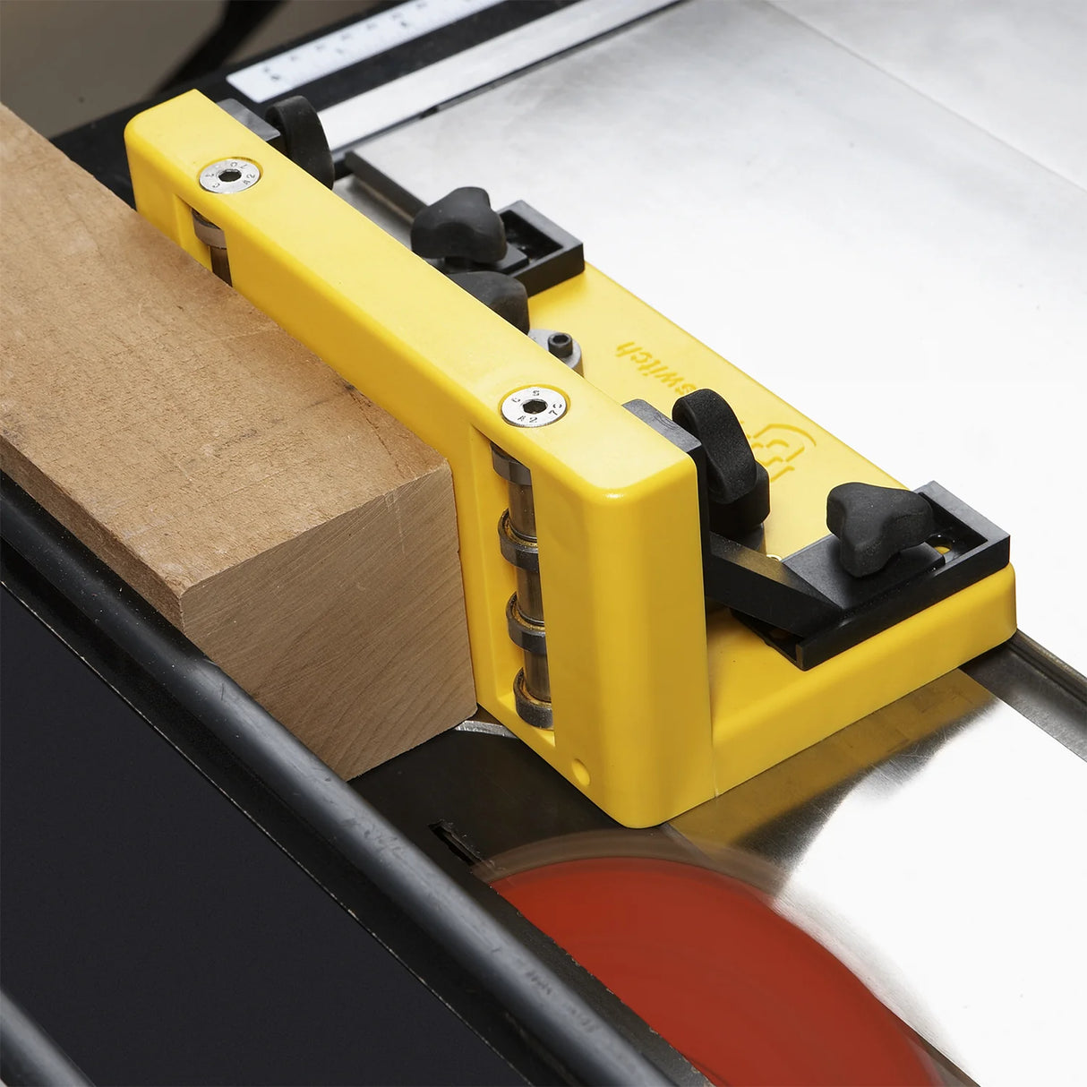 Yellow woodworking table saw safety guide with block of wood on saw blade