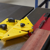 Table saw with yellow featherboard, wood being cut, woodworking safety accessory