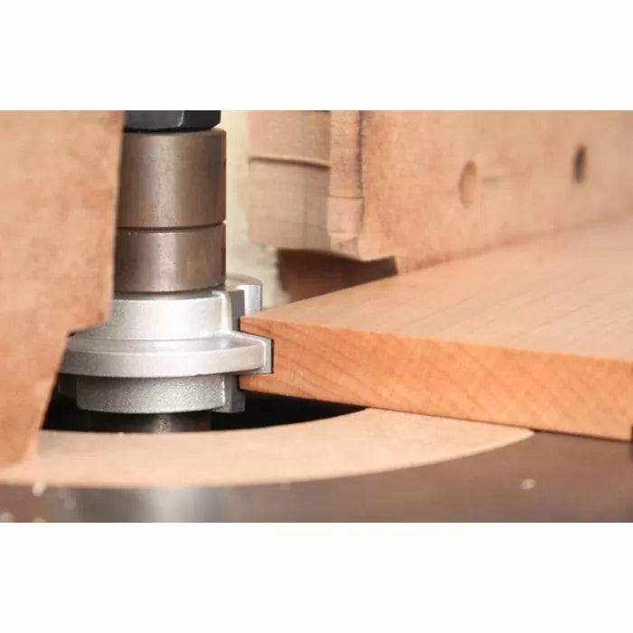 Router table with cutter head grooving a wooden board for woodworking joinery