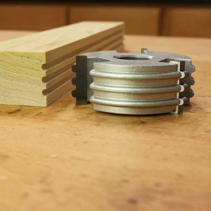 Groove cutting woodworking cutter head and matching profiled wood on workbench