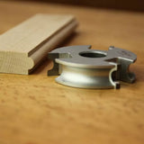 Profile woodworking cutter head with finished molding on wood surface