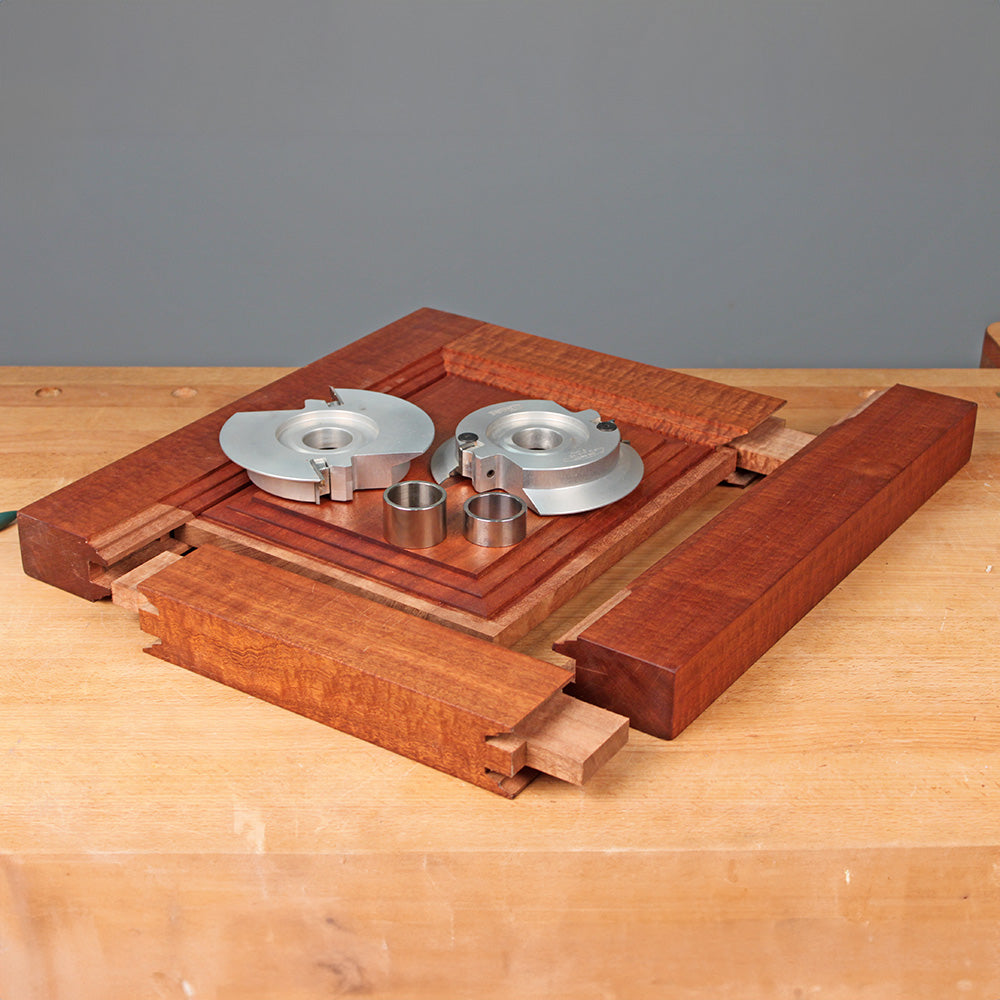 Woodworking shaper cutter set with steel router bits and tenon joints on a wooden workbench