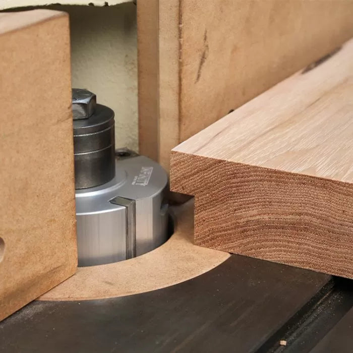 Woodworking router bit cutting a profile on a wooden board with precise setup