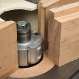 Heavy-duty woodworking shaper cutter installed on a table, surrounded by wood pieces