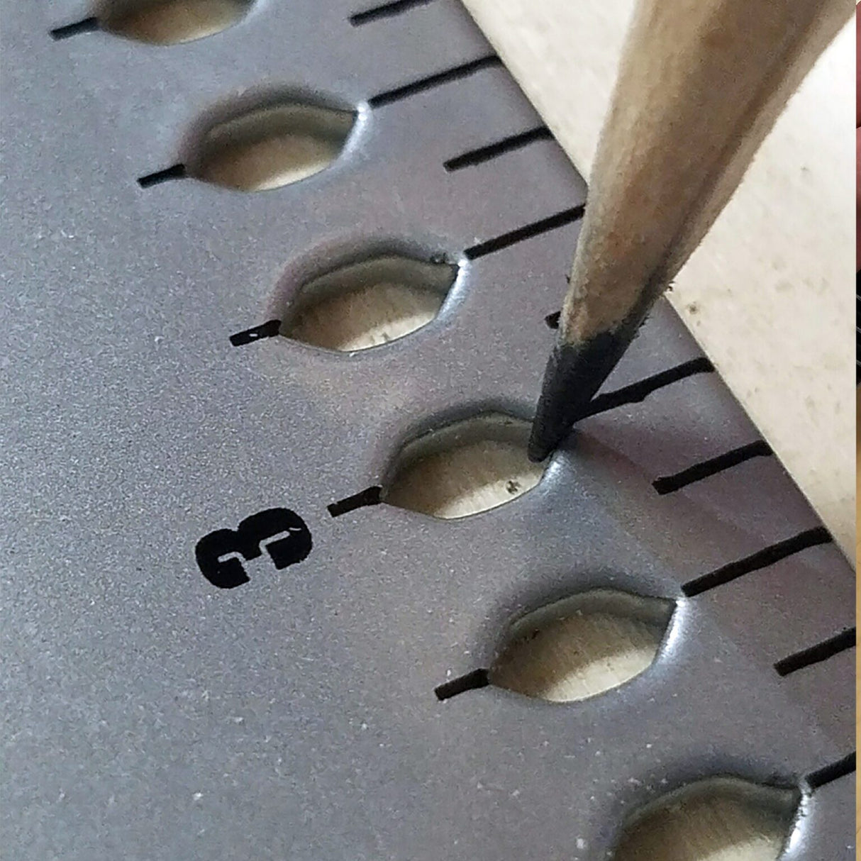 Close-up of marking layout points through the FrameSquare's holes with a pencil