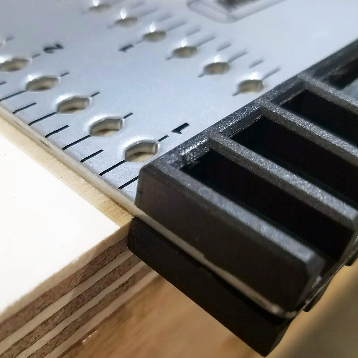 Close-up of the Milescraft FrameSquare's fence registered against the edge of a plywood panel