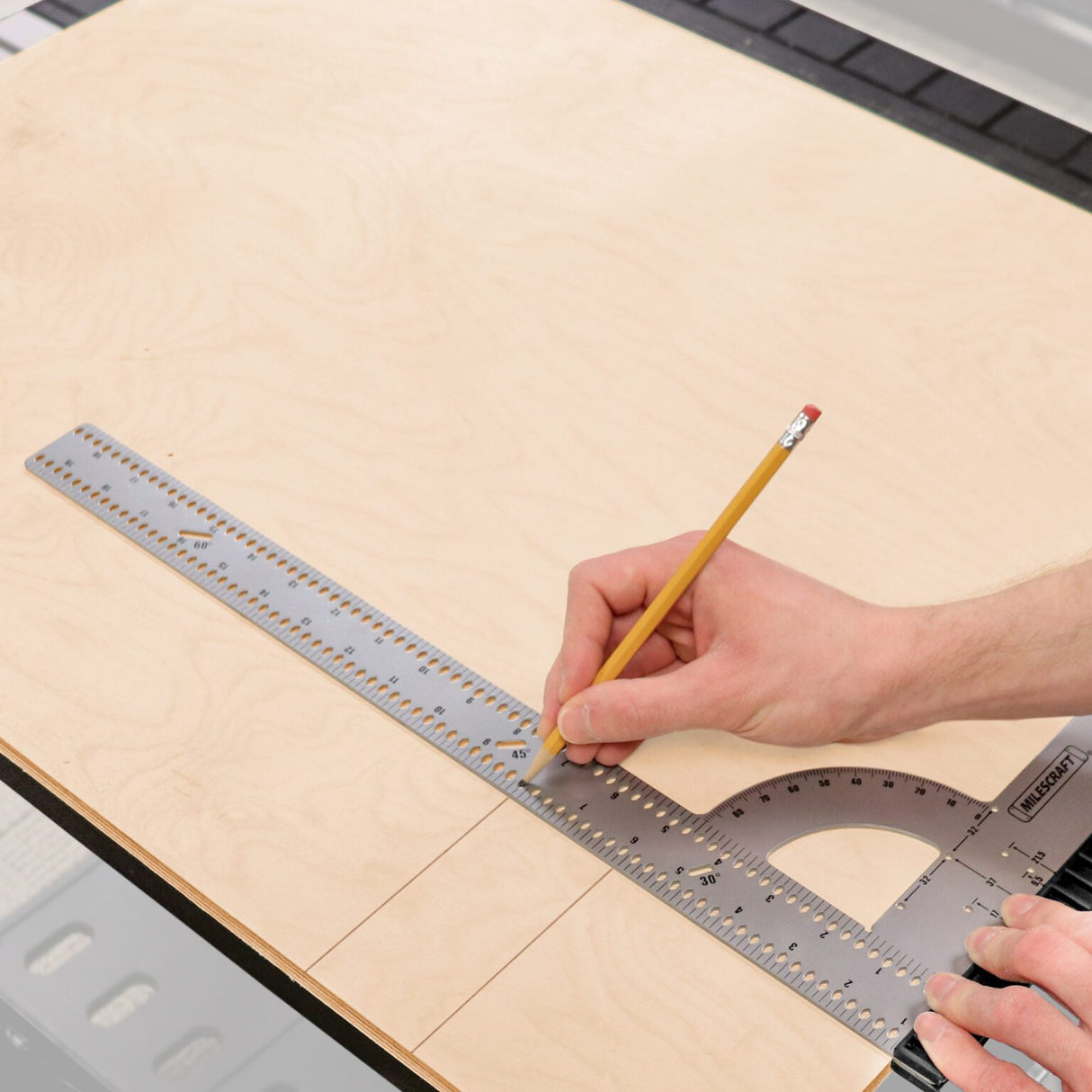 Marking a straight line along the Milescraft FrameSquare's ruler on a plywood panel