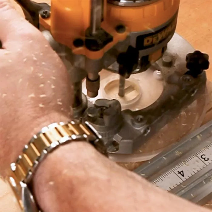 Hand guiding a woodworking router over wood next to a ruler, cutting a round groove.