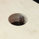 Close-up of a flush trim router bit cutting a circular hole in plywood.