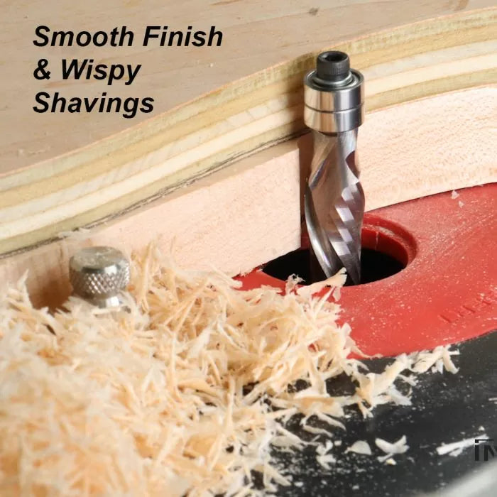 Spiral router bit cutting plywood on a router table with fine wood shavings and smooth finish.