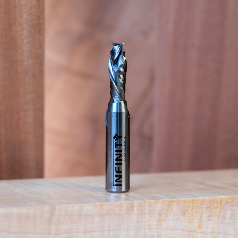 Carbide spiral router bit standing upright on a wood surface with engraved label visible.