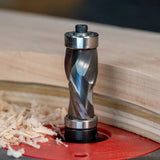 Spiral flush trim router bit cutting wood on a router table with wood shavings nearby