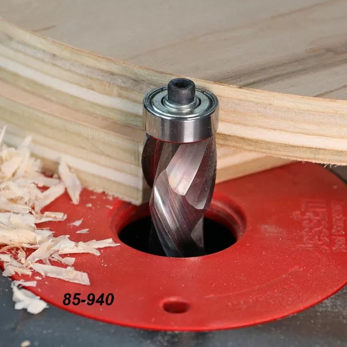 Flush trim router bit cutting plywood on a router table with wood shavings visible.