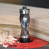 Spiral flush trim router bit mounted in a router table, cutting curved wood with wood shavings.