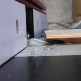 Close-up of a router table with plywood, showcasing woodworking precision and router bit action.