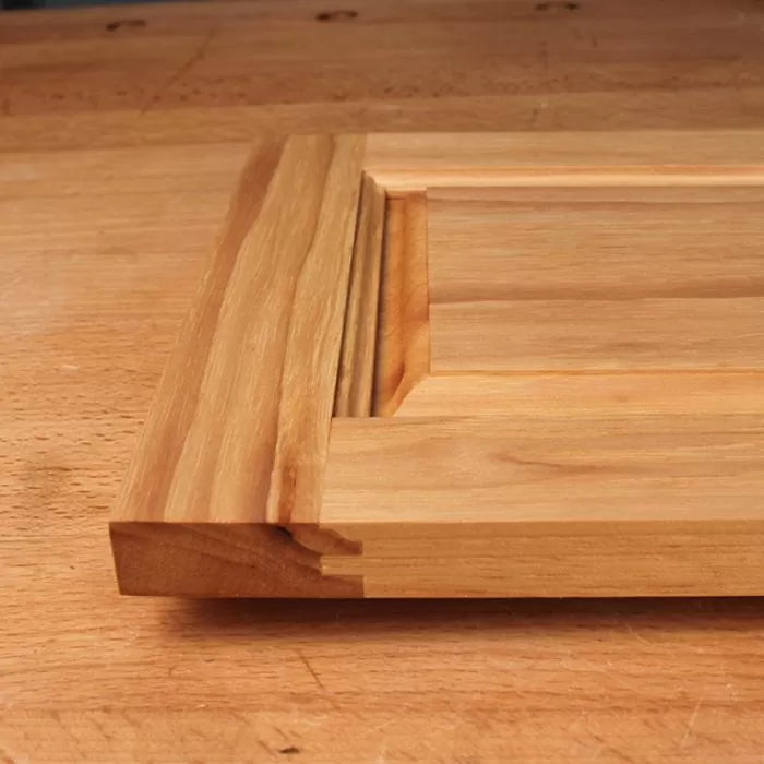 Close-up of unfinished raised panel cabinet door with decorative wood profile on workbench
