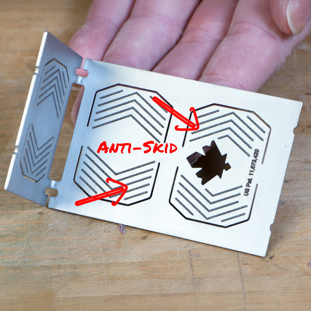Anti-skid metal woodworking jig with etched grip patterns and cutouts, held by hand