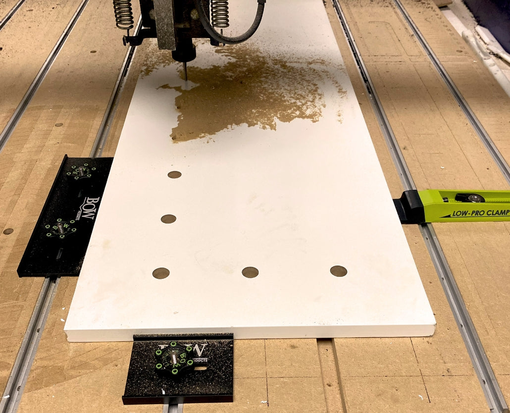 CNC router cutting wood panel secured with Bow and Low-Pro clamps, woodworking setup