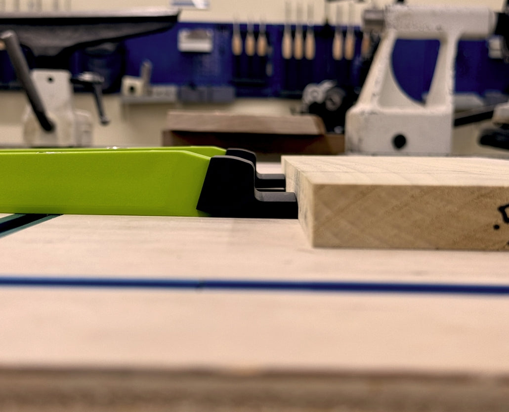 Bow clamp holding wood piece on workbench in woodworking shop setting