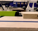Bow clamp holding wood piece on workbench in woodworking shop setting