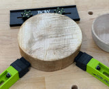 Bow woodworking clamps securing a round wood blank on a workbench
