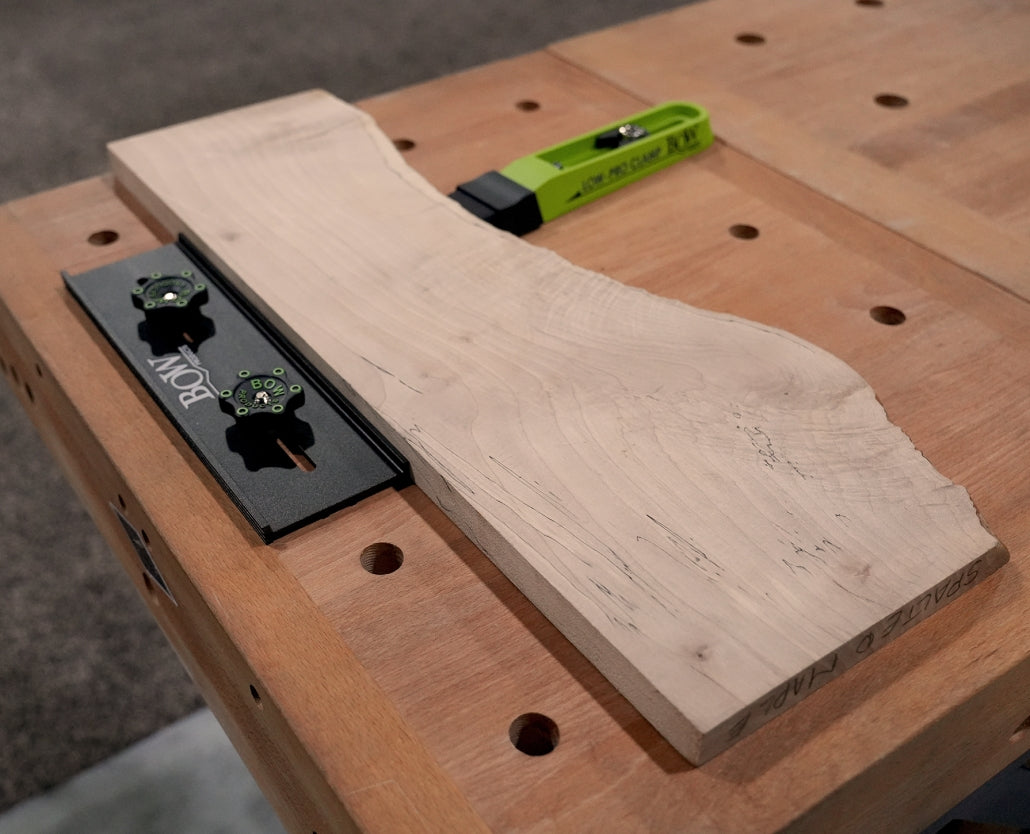Bow clamp system securing live edge wood board on workbench for woodworking