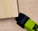 Green bow clamp holding wooden board on a workbench for woodworking projects