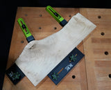 Bow clamps securing rough wood slab on woodworking bench for precise cutting or shaping