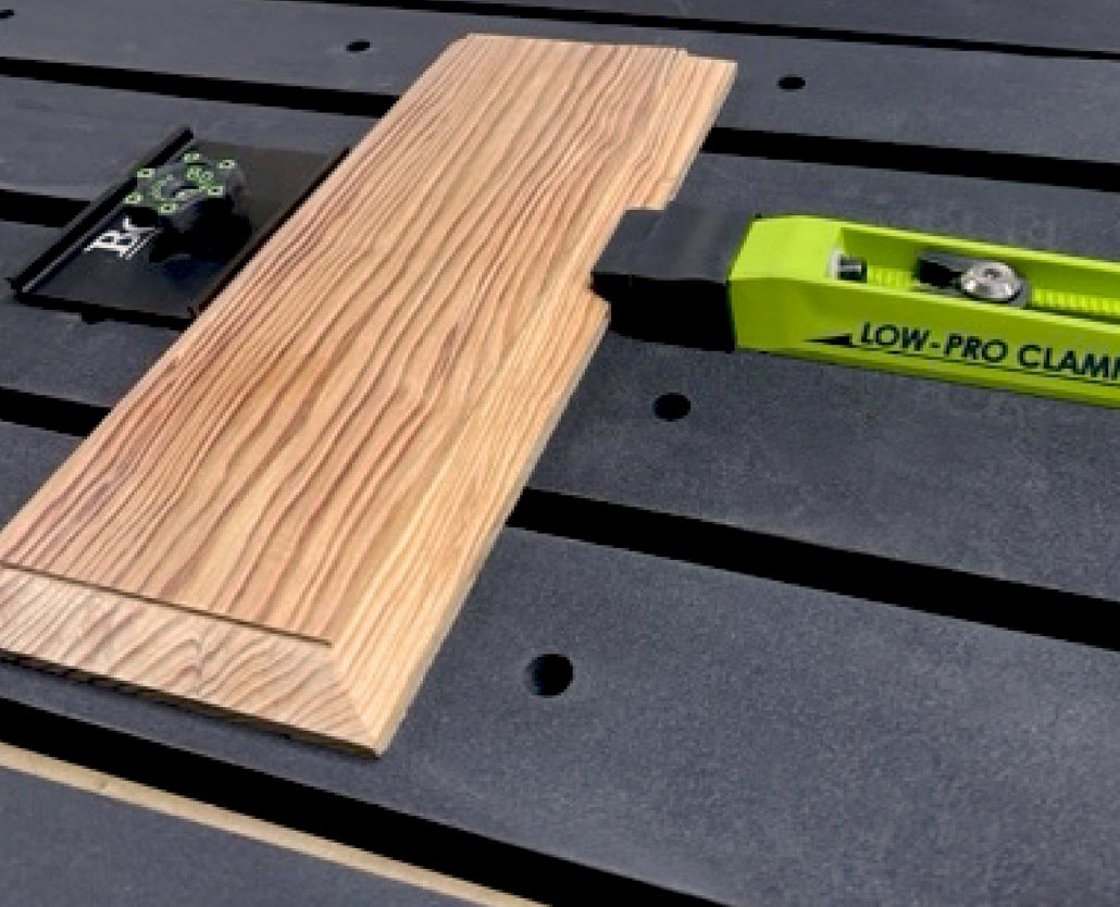 Low-profile woodworking clamp securing a wood board on a workbench