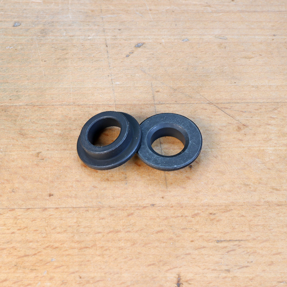 Steel router guide bushings on wooden workbench, woodworking tool accessories