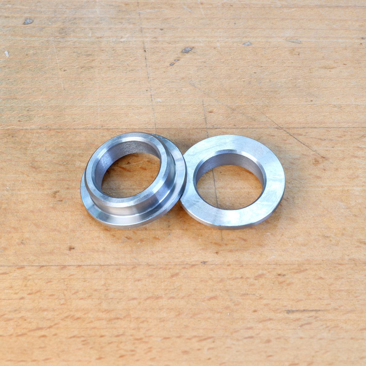 Two metal router table reducer rings on a wooden surface, woodworking tool accessory