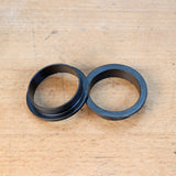 Black router table reducer rings on a wooden surface, woodworking tool accessory