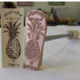 Woodburning branding iron with pineapple design and marked wooden sample, woodworking tool
