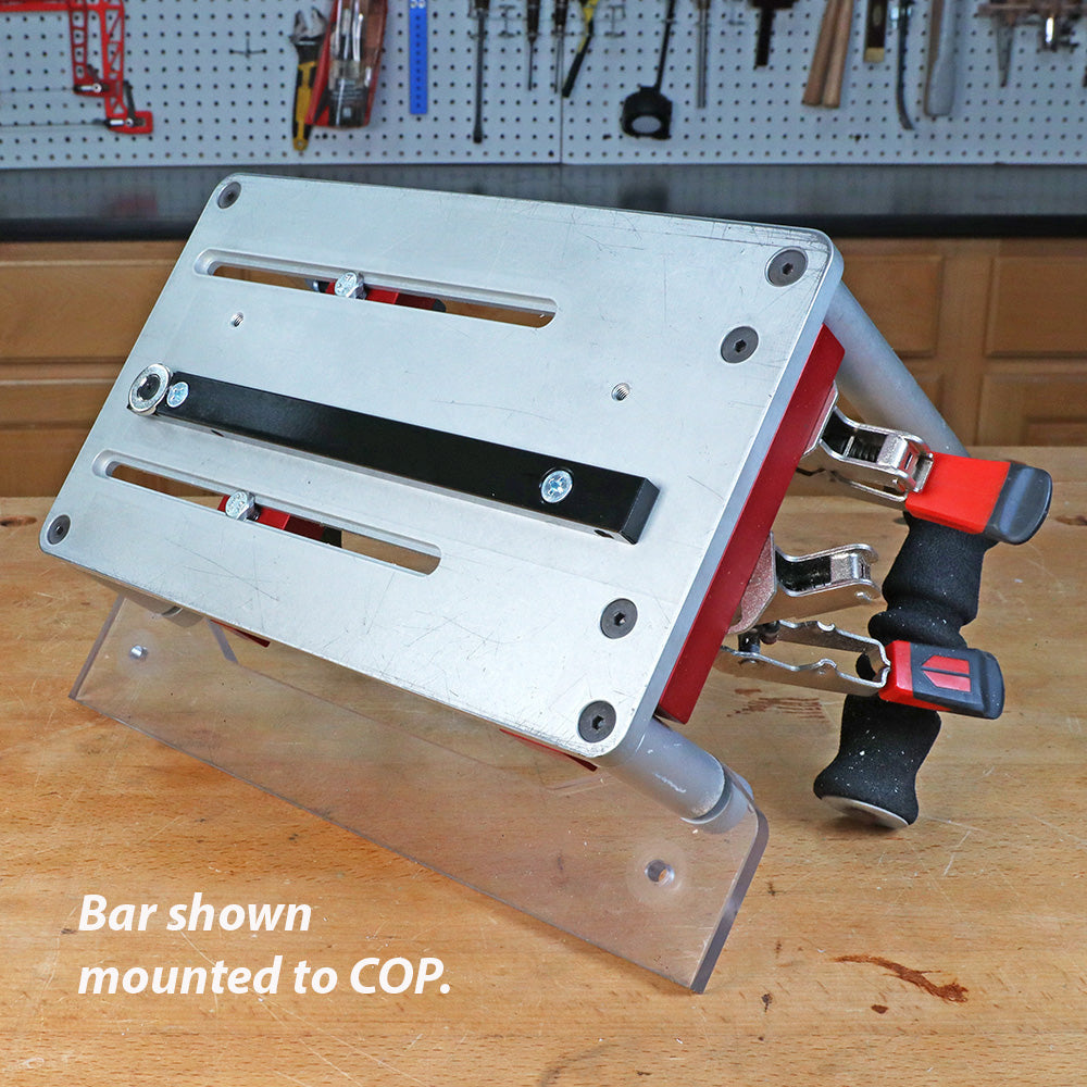 Metal jig with mounted bar and clamping handles on workbench in woodworking shop