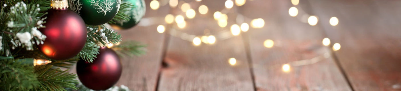 Christmas tree branches with red and green ornaments, string lights, and rustic wood background