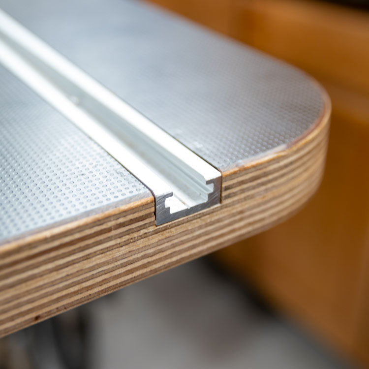 Close-up of router table edge with aluminum T-track for woodworking jigs and accessories