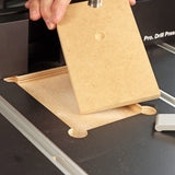 Drill press table with replaceable MDF insert and woodworker's hand during woodworking setup
