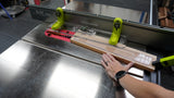Table saw with fence and safety guides cutting wooden board in woodworking shop
