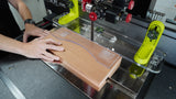 Person using a bandsaw with a safety guide to cut a curved shape in hardwood block