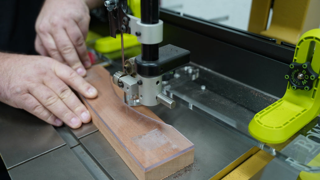 Woodworker using a bandsaw to cut a curved piece of wood with precision woodworking tools
