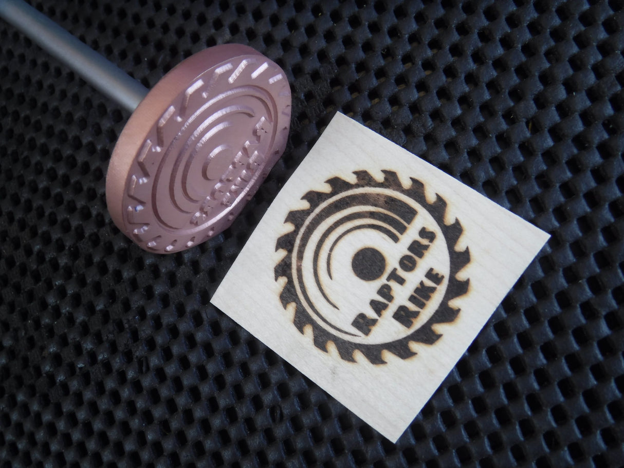 Custom branding iron with saw blade design and wood burned logo on textured mat