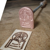 Wood branding iron with custom engraving and stamped mark on wood, on a workbench