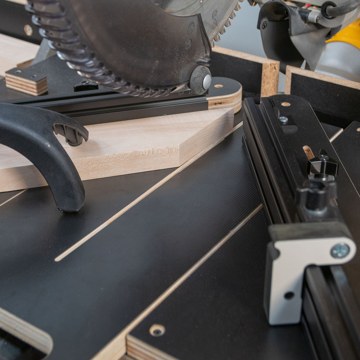 Miter saw jig cutting wood at an angle on a precision woodworking workstation.