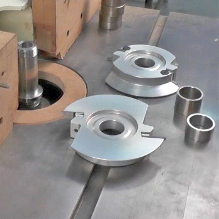 Industrial woodworking shaper cutter heads and spacers on a metal router table setup