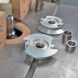 Industrial woodworking shaper cutter heads and spacers on a metal router table setup