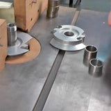 Industrial woodworking cutter heads and spacers on a metal table saw surface
