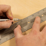 Hand using pencil and metal ruler for precise woodworking measurement on wood surface